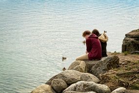 romantic couple sitting on the beach rock