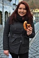 girl is eating a pretzel on a street in Passau