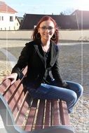 Girl with red hair is sitting on the bench