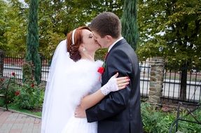 Kiss of the bride and groom among the park