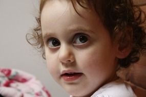 portrait of a little girl with curly hair close-up on blurred background