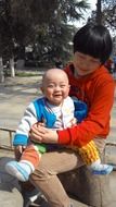 mother with baby sitting on stump