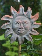 Ceramic decor in the form of the sun among the park