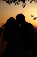 black silhouette of a kissing couple in love on a sunset background