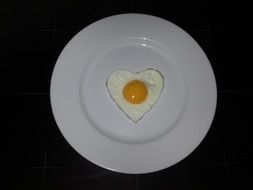 fried eggs in the shape of a heart on a plate