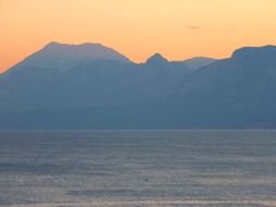 view from the water to the mountains at sunset
