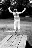 girl is jumping from a wooden bench