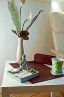 Buddha figurine, cup and vase on table