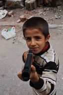 boy playing with a gun on the street