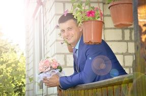 happy groom in a blue suit in the rays of the bright sun