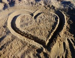 heart is drawn on the sand on the beach