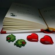 two glossy hearts at open book on desk