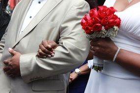 Hands of the groom and the bride with a bouquet