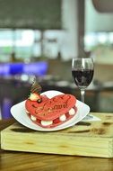 heart-shaped cake and a glass of red wine