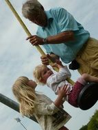 grandfather shakes grandchildren on a swing