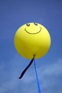 Yellow smiley balloon in the blue sky background