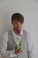 Young man in a suit with a flower in his hands