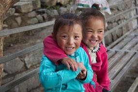 happy asian kids sitting on a bench