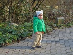 Child in a green jacket walking