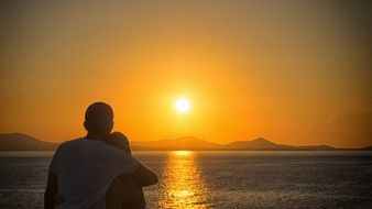 young couple is watching an orange sunset