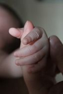 newborn baby holds mom by the finger