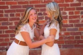 two beautiful happy caucasian girls at brick wall