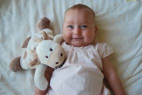 a small child with a smile lies on the bed