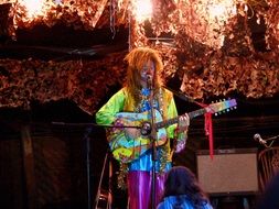 colorful hippie playing guitar, outdoor concert