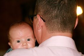 baby boy looking from dadâs shoulder