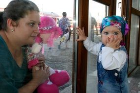 mom and daughter look at each other through the window