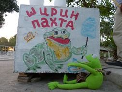 painted portrait of a frog and Kermit Frog sits