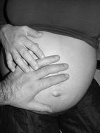 man hand on pregnant woman’s belly