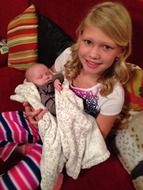 little girl blonde with a baby in her arms
