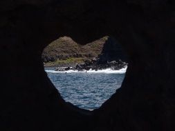 view of tropical beach through heart form hole in rock, usa, hawaii, maui