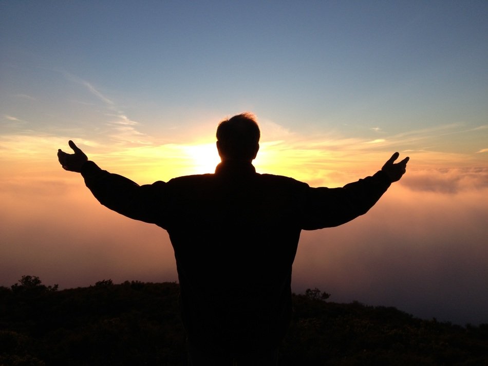 silhouette of a man in prayer at sunset