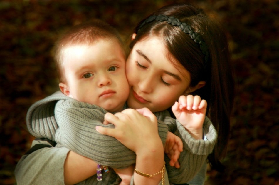 portrait of child girl hugging her baby brother