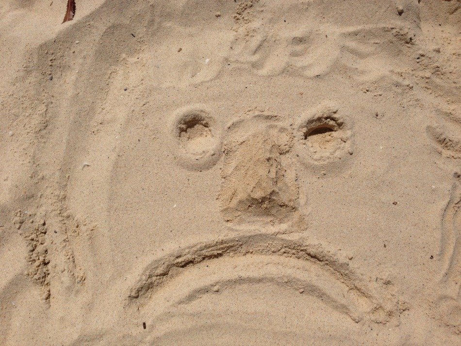 sad face sketch on sand