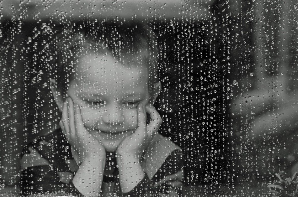 boy near the window during the rain