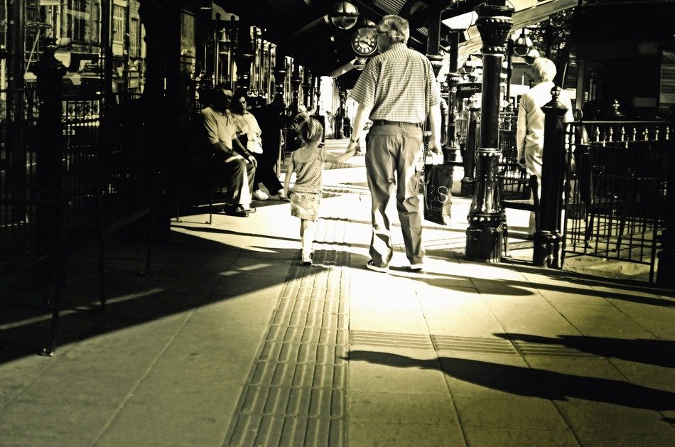 black and white image of grandfather with granddaughter on a city street