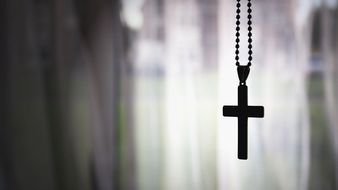 photo of a cross on a chain on a muddy background