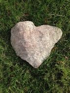 stone in the shape of a heart lies on green grass