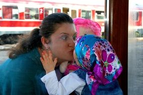 Mom and daughter are kissing through the window