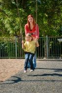 mom shakes her daughter on a swing