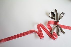 spoon fork and knife tied up with a red ribbon