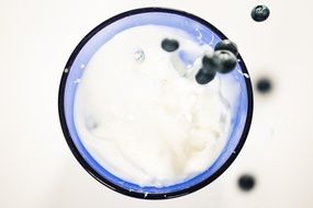 bluberries falling into a glass of milk