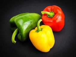 red, green and yellow paprika at black surface