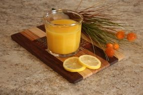 fresh orange juice with lemon and flowers on a wooden surfaces