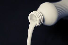 liquid milk flowing out of white plastic bottle