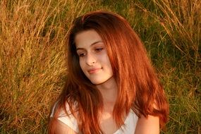 portrait of a girl with foxy hair on a background of autumn grass