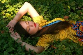 Girl with closed eyes in a yellow dress on a background of grass